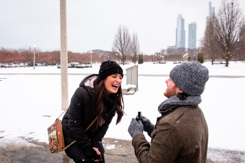A man and woman are laughing while standing in the snow.