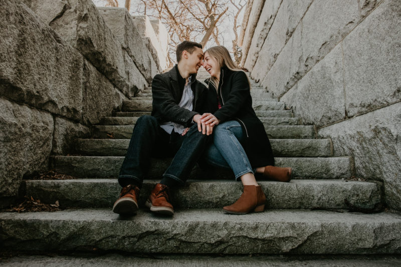 A man and woman sitting on stone steps captured by Chicago engagement photographer, Beloveful Photography.