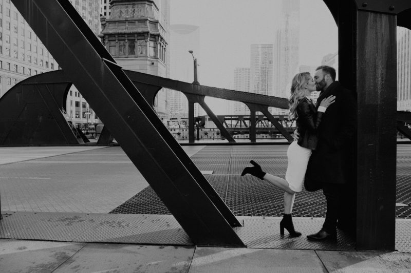 An engaged couple sharing a kiss on a bridge, captured by Beloveful Photography in Chicago.