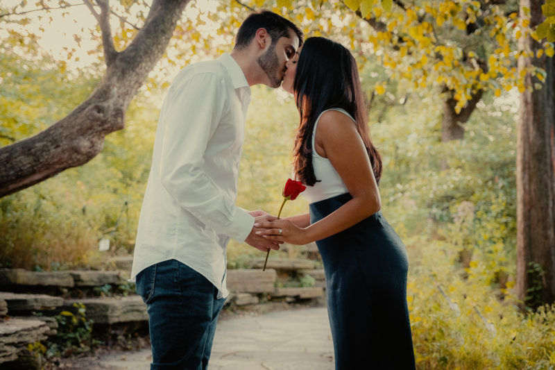 An engaged couple kissing in the woods captured by Beloveful Photography.